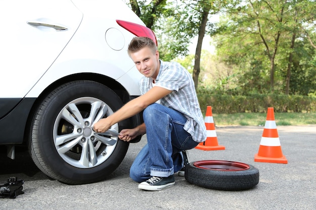 Man driver having trouble at road changing wheel