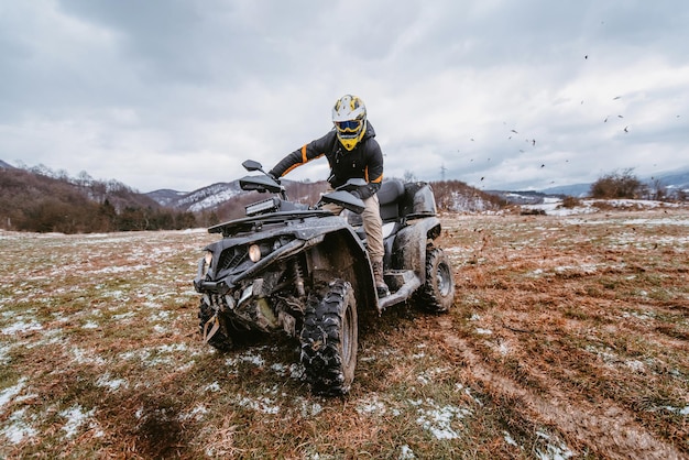 a man drives an atv in the mud drift driving an atv quad in mud and snow