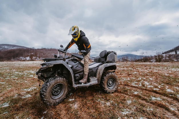 A man drives an atv in the mud drift driving an atv quad in mud and snow