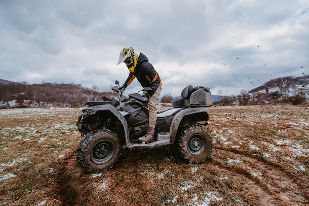 A man drives an atv in the mud drift driving an atv quad in mud and snow