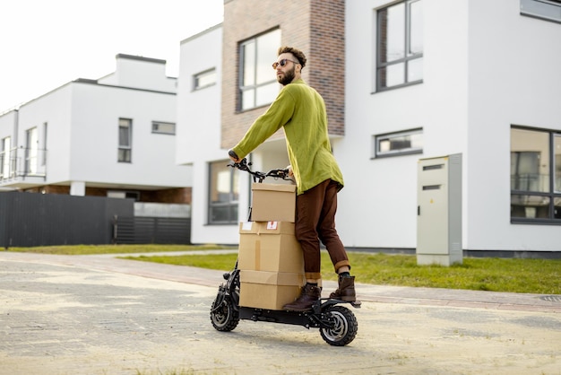 Мужчина водит электрический скутер с картонными упаковками
