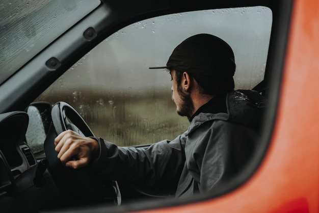 雨が降っている間に赤いバンを運転している男