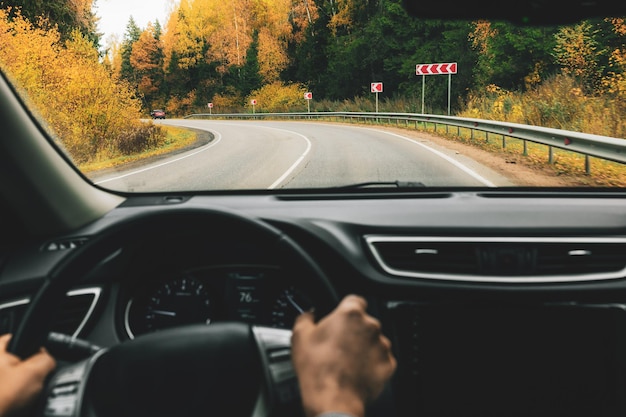 Man driving car on the country road in autumn