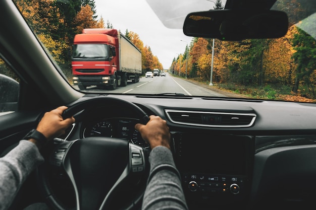 Man driving car on the country road in autumn