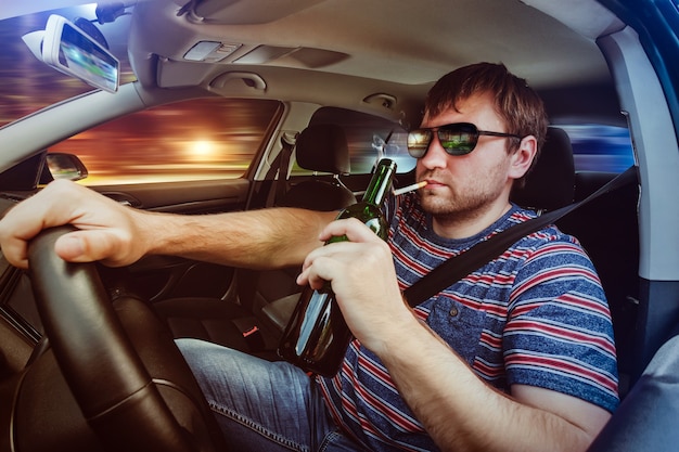 車を運転してビールを飲む男