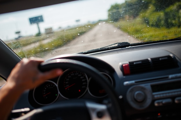 Photo a man driving a car, focus on the left hand held on steering wheel.