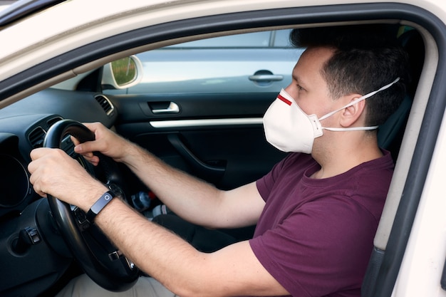 A man driving a car in a medical face mask during an epidemic