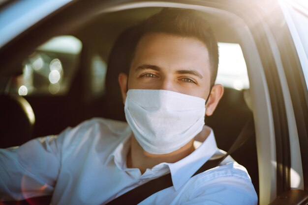 Man driving a car puts on a medical mask during an epidemic in quarantine city.