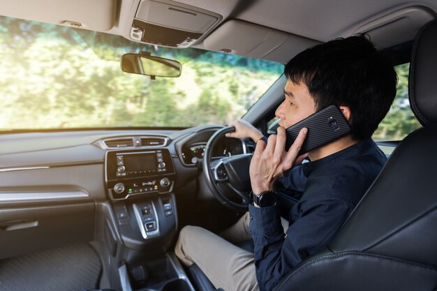 車を運転し、携帯電話で話している男