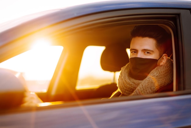 Man driving a car wearing on a medical mask during an epidemic Transport isolation Covid2019