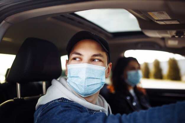 滅菌医療マスクを着用して車を運転する男