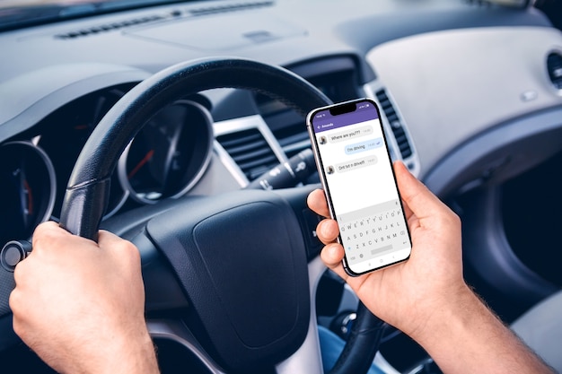 Man driving a car with a phone in his hand