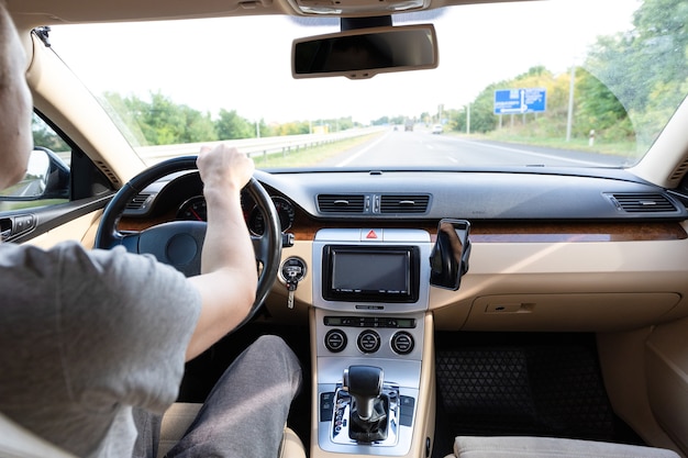 アスファルト道路で現代の車を運転する男