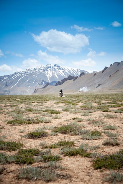 Man driving a motorbike in a valley in the himalayas ladakh india vertical shot road trip