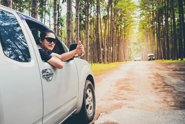 A man Driving a pickup truck Through rough paths Which is a way in the middle of pine forest