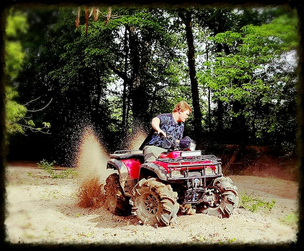 Man driving quadbike in dirt against trees