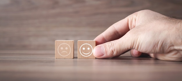 Man droevige en gelukkige smileys waarop houten kubus. Klanttevredenheid