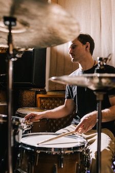 Uomo batterista che suona la batteria in studio di registrazione