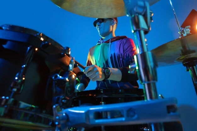 Man drummer playing on neon light