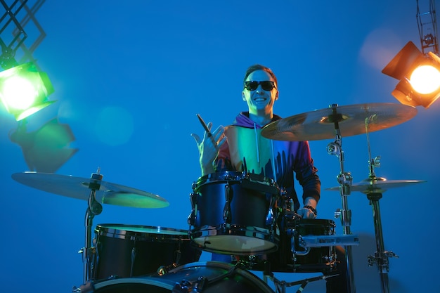 Man drummer spelen op neonlicht