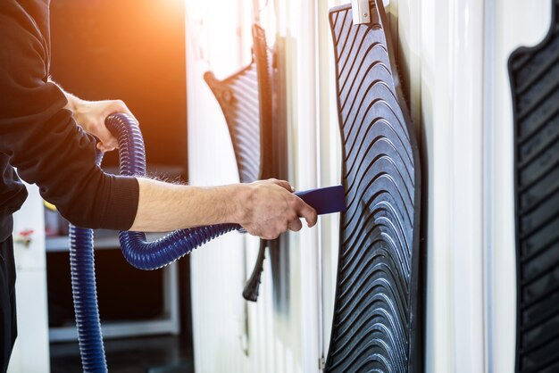 Man drying car carpet with vacuum cleaner after washing