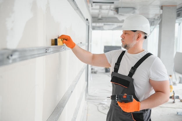 Man drywall worker installing plasterboard sheet to wall