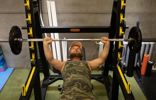 Photo man during bench press exercise with barbell in gym