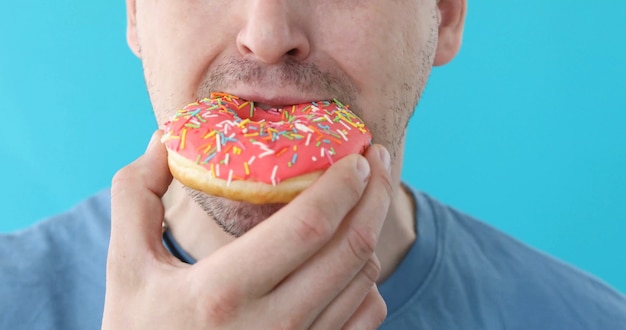 Man eat donut closeup on blue 