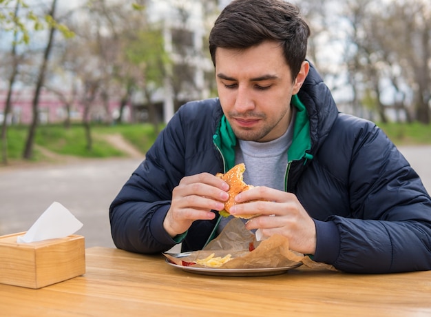 Uomo che mangia un hamburger in un caffè di cibo di strada