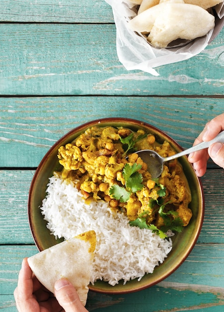 Man eating cauliflower spicy curry rice naan bread top view