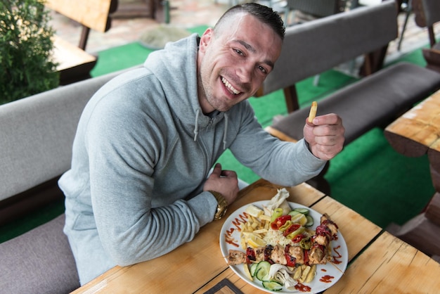 Man eating chicken with rice in outdoor restaurant