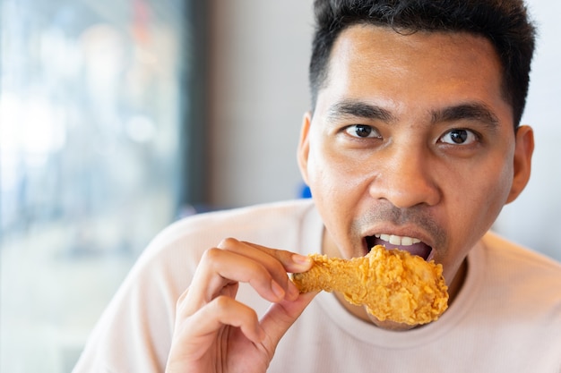 man eating  fried chicken leg in brunch meal at restaurant with happiness in relax time 