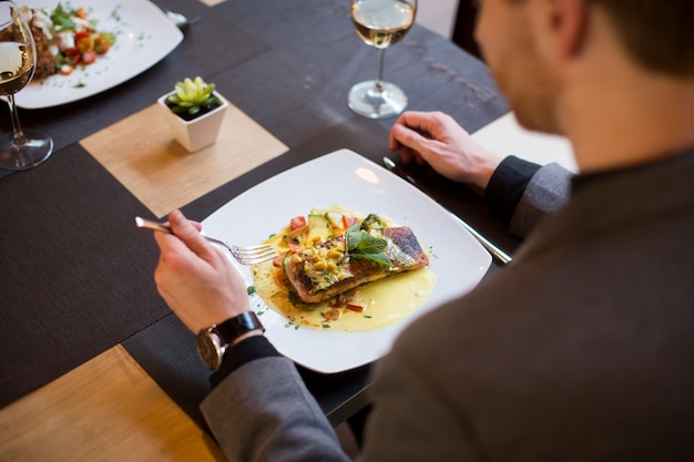 レストランで焼かれたサーモンを食べる男