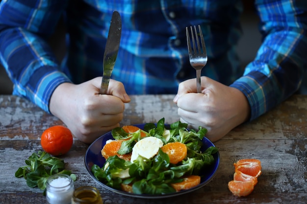 写真 みかん、モッツァレラチーズ、マッシュサラダと一緒にヘルシーなサラダを食べる男性。