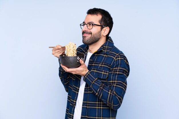 Man eating noodles over isolated wall