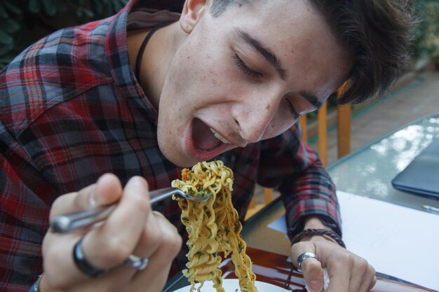 Foto uomo che mangia tagliatelle al ristorante