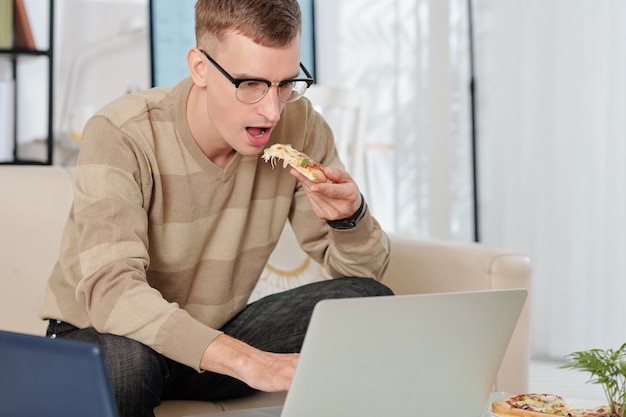 ピザを食べて電子メールを読む男