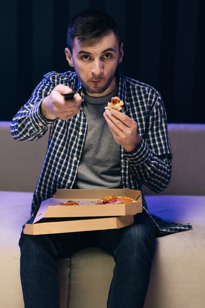 man eating pizza watching favorite film on tv