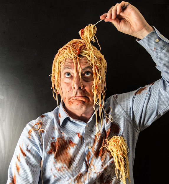 Человек ест спагетти с томатным соусом в голове