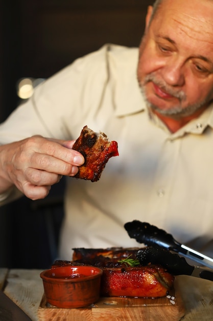 Man eating tasty grilled pork ribs