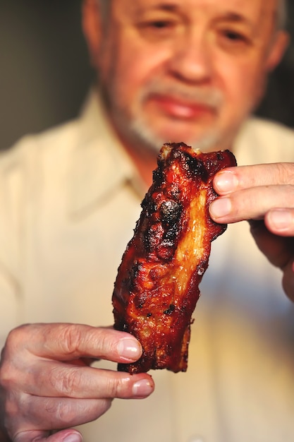 Man eating tasty grilled pork ribs