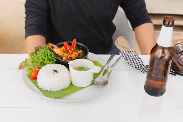 Man eating Thai famous dish pad kra pao stream rice with king prawn on vacation