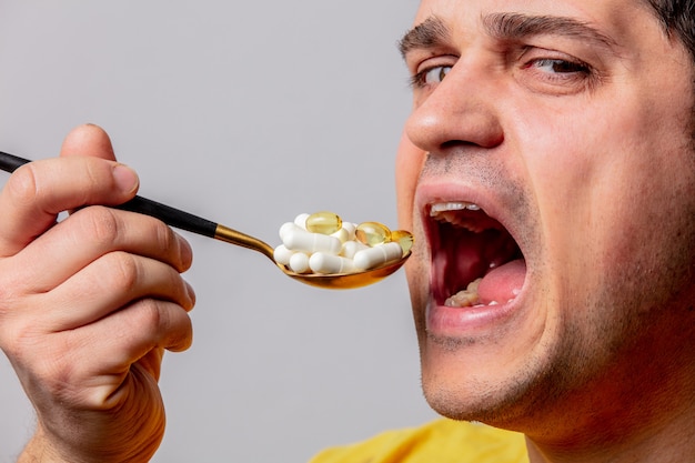 Человек ест таблетки с ложкой | Премиум Фото
