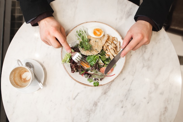 男は彼の手にフォークとナイフで肉の食欲をそそるサラダを食べる