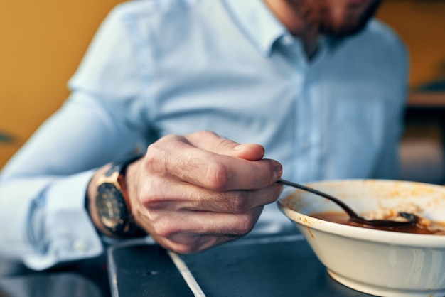 한 남자가 카페의 테이블과 그의 손에 시계에있는 레스토랑에서 사워 크림과 함께 보르시를 먹는다.