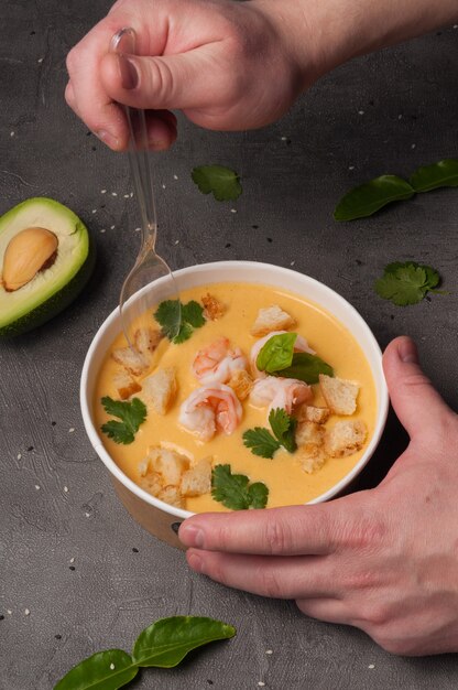 A man eats cheese soup with shrimp and croutons. vertical frame