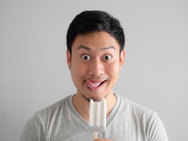 Man eats ice pop with funny face.