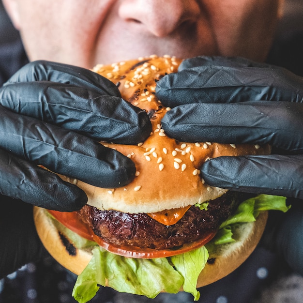 男はジューシーなビーフバーガーを食べます。閉じる