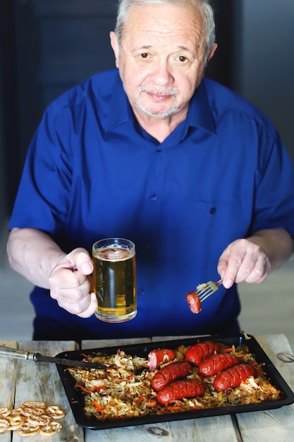 A man eats sausages with sauerkraut and beer.