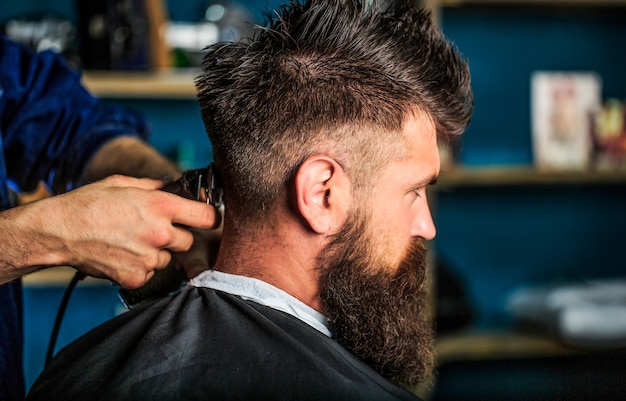 Man een bezoekende haarstylist in de kapsalon. kapper werkt met een tondeuse